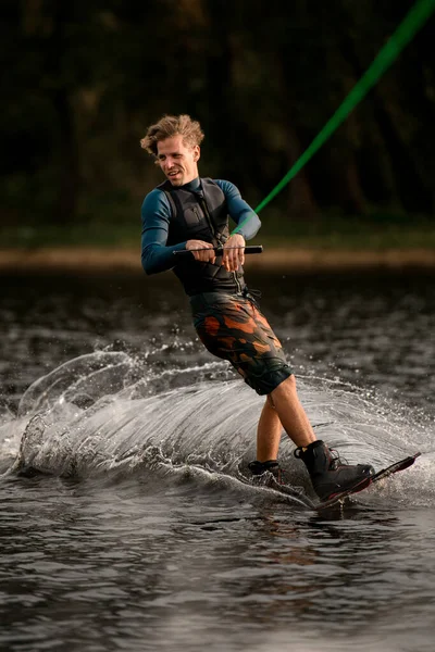 健康的运动员骑在滑板上，在河里掀起了大量的水花 — 图库照片