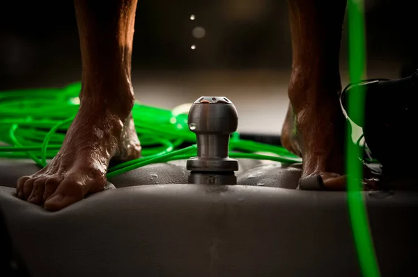 Közeli kép a férfi lábak álló motorcsónak és zöld kötél fekszik a közelben — Stock Fotó