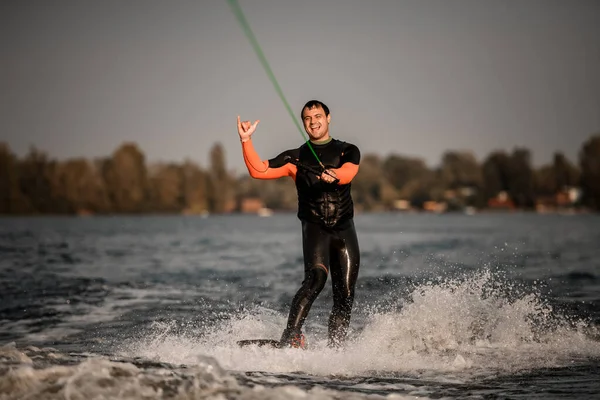 Веселий чоловік показує жест під час їзди по хвилі на дошці — стокове фото