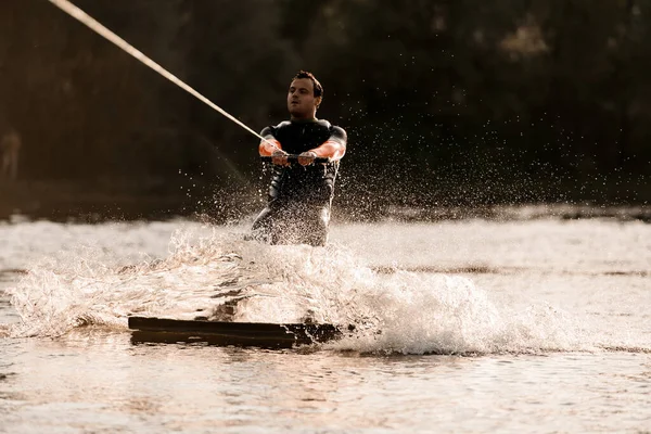Man in wetsuit is bezig met extreme watersporten en ritten op wakeboard — Stockfoto