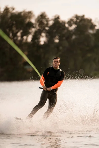 Verraste man houdt strak kabel in zijn handen en balanceert op golf op wakeboard — Stockfoto