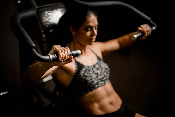 Detailní záběr ženy, jak cvičí na simulátoru. Pojetí sportu, tělocvičny, sportovní oblečení, fitness. — Stock fotografie