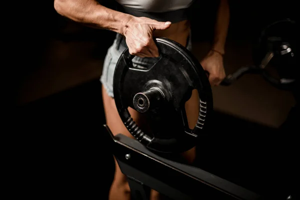Närbild på detaljer av skivstång. Idrottare kvinnor händer förbereda utrustning för bodybuilding träning. — Stockfoto
