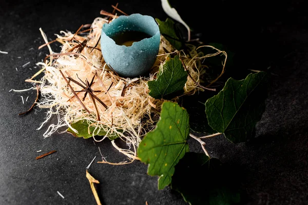 Huevo en cáscara acristalada azul en nido de fibra de madera decorado con hojas verdes — Foto de Stock