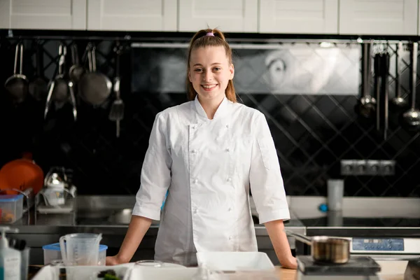 Bonito jovem sorridente mulher chef no cozinha — Fotografia de Stock