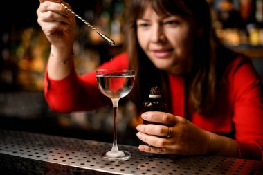 Sıvı katılmış cam yakın plan. Kadın içeriğini damla damla ekliyor.