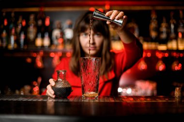 Cam barın üzerinde durur ve kadın barmen ustaca doldurur jigger 'dan içkiyi içine