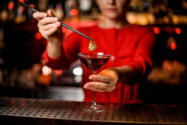 İçkili cam alkolik manzarası. Cımbızla kadın eli hoplayarak güzelce dekore ediyor.