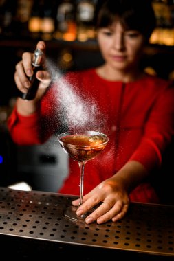 Barın tezgahında duran bardaklar ve üzerine doğru barmenler serpiştirilmiş.