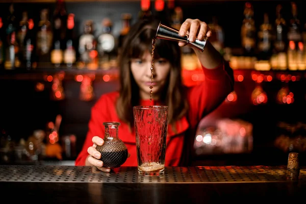 Vidro fica no bar e barman mulher cuidadosamente derrama vinho de jigger para ele — Fotografia de Stock