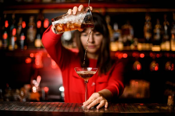 Vista sul bicchiere da vino in piedi su bar e barista che tiene il bicchiere di miscelazione e bevande accurate in esso — Foto Stock