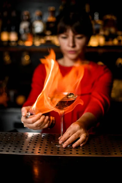 Barista femminile tiene il vetro sul bancone del bar e lo dà fuoco — Foto Stock