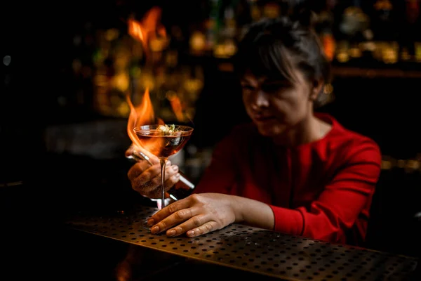 Great view on glass on bar counter which lady barman masterfully sprinkles and sets fire — Stock Photo, Image