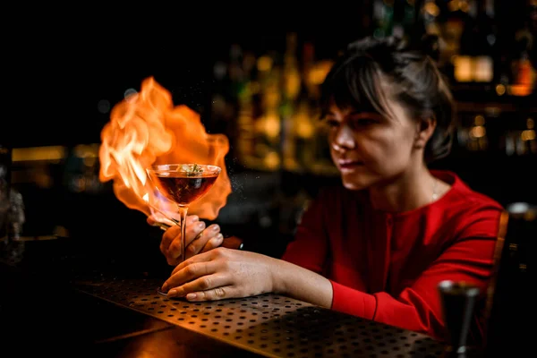 Beautiful view on wine glass on bar counter which lady barman masterfully sprinkles and sets fire — Stock Photo, Image