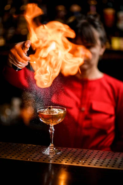 Weinglas mit Eisgetränk steht auf der Theke und Barfrau bestreut und setzt es in Brand — Stockfoto