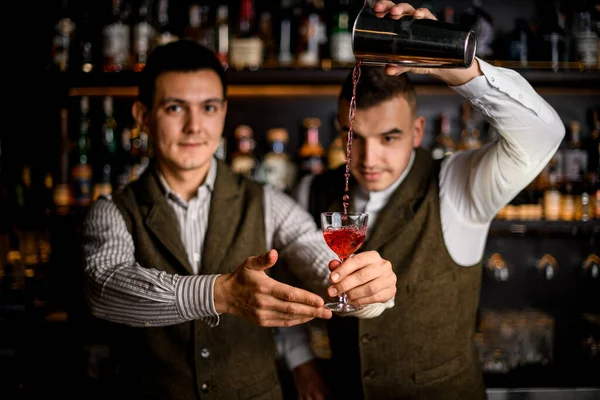 Homem barman detém vidro e outro homem magistralmente derrama coquetel nele — Fotografia de Stock