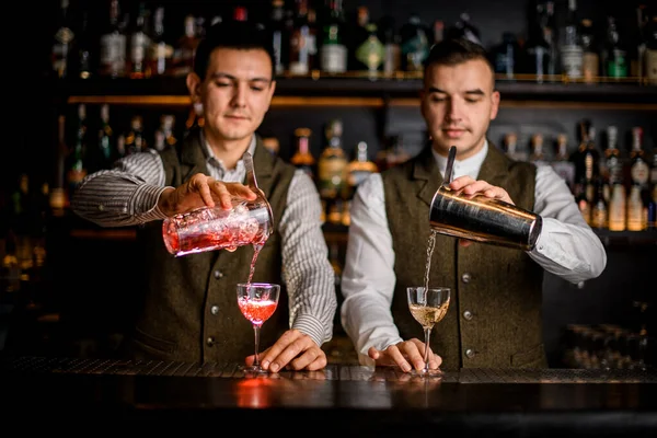 Visão de copos de coquetéis alcoólicos nos quais os empregados de bar cuidadosamente vazam bebidas ao mesmo tempo — Fotografia de Stock