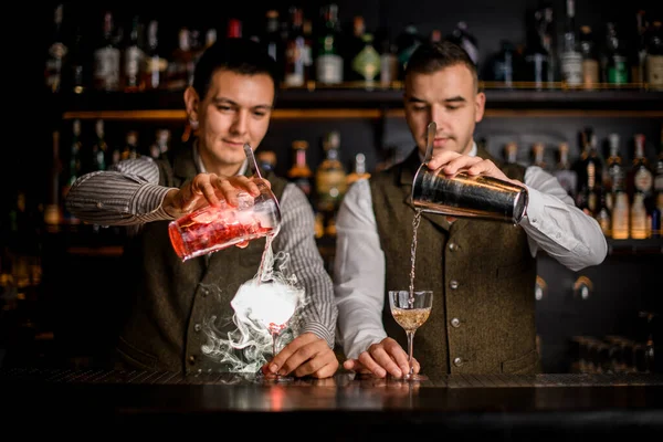 Visão de copos de coquetéis alcoólicos nos quais os empregados de bar vazam bebidas ao mesmo tempo — Fotografia de Stock