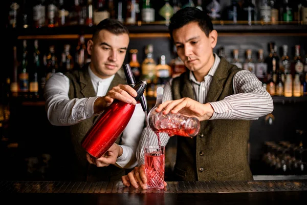 two men bartenders preparing alcoholic cocktail at bar.