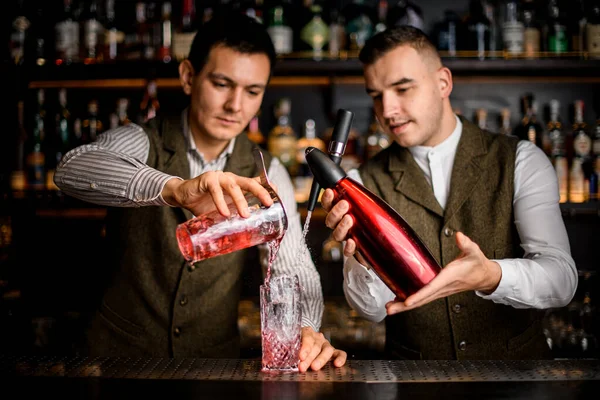 Два профессиональных бармена готовят алкогольный коктейль в баре. — стоковое фото