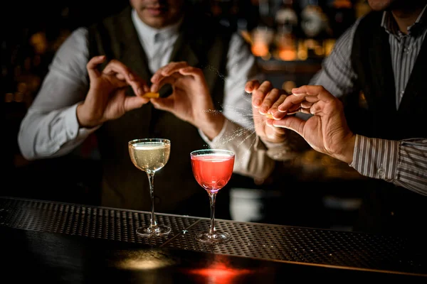 Blick auf Gläser mit Getränken, auf die Barkeeper Zitrusschalen streuen — Stockfoto