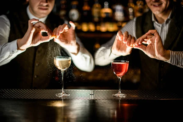 Óculos ficar na barra, enquanto os bartenders masculinos precisos polvilhar suco de raspas sobre eles — Fotografia de Stock
