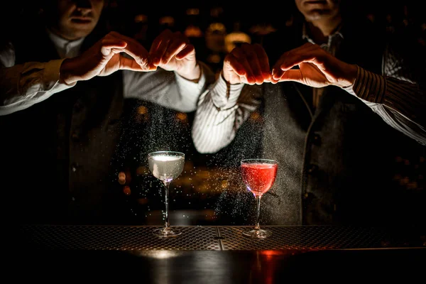 Óculos ficar no bar, enquanto bartenders masculinos polvilhar suco de raspas sobre eles — Fotografia de Stock