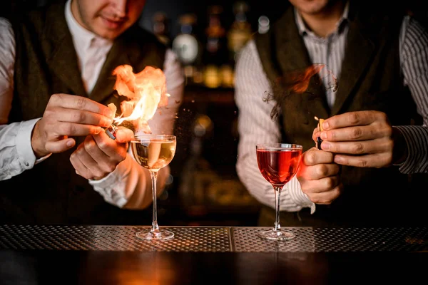 Bardaklara içki ve profesyonel barmenlerin serpiştirilmesini ve ateşe verilmesini.