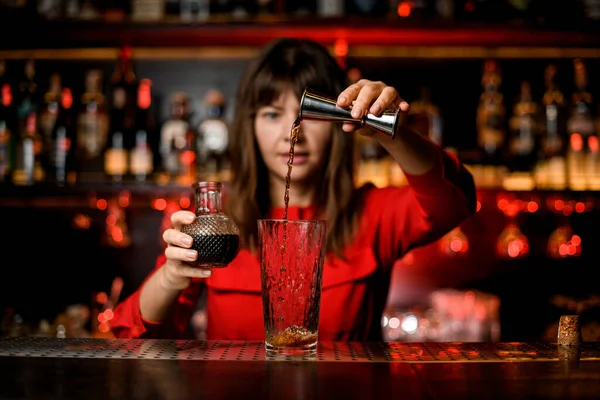 Vidro fica no bar e mulher barman magistralmente derrama bebida de jigger para ele — Fotografia de Stock