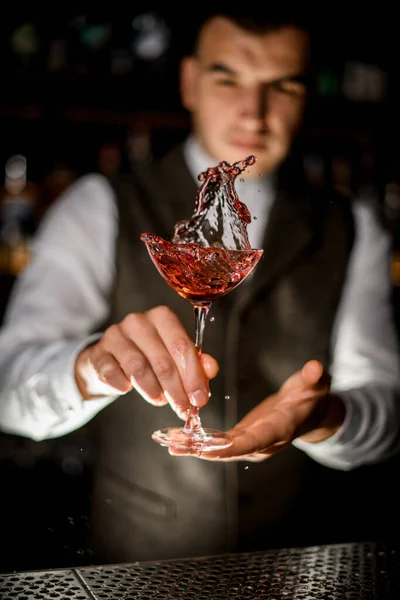 Vista de vidro de bebida vermelha salpicada nas mãos do homem — Fotografia de Stock