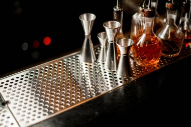 Üzerinde bir kaç jigger ve içki şişesi olan harika bir bar manzarası.