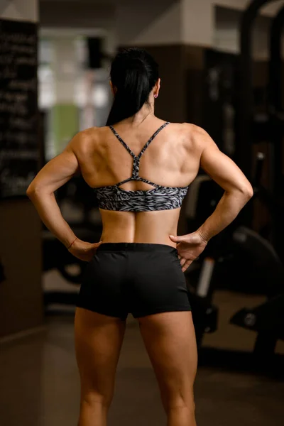 Spor giyim sektöründe sağlıklı ve güçlü bir kadının spor salonunda dikilirken — Stok fotoğraf