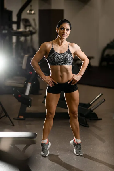Ganzes Porträt der attraktiven, muskulösen Bodybuilderin, die im Fitnessstudio auf Zehenspitzen steht — Stockfoto