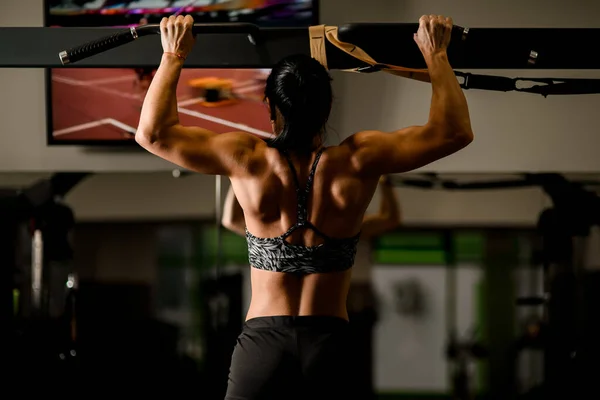 Närbild av muskulös kvinna gör pull ups i gymmet. Koncept för kroppsbyggnad. — Stockfoto