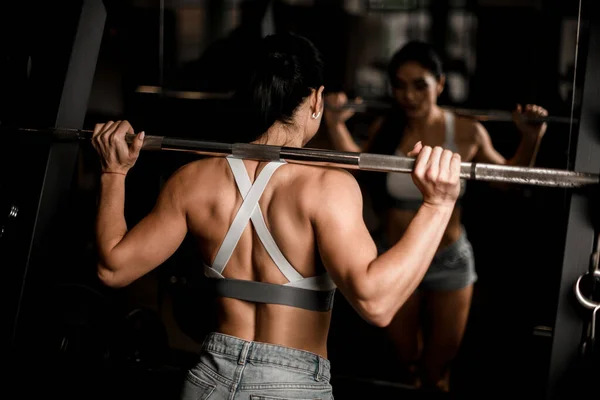 Närbild av vuxen brunett kvinna som tränar med skivstång i gymmet. — Stockfoto