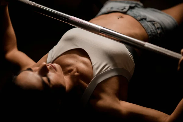 Spor salonunda halteri yukarı iterek yoğun çalışma yapan kadının yakın çekim görüntüsü.. — Stok fotoğraf