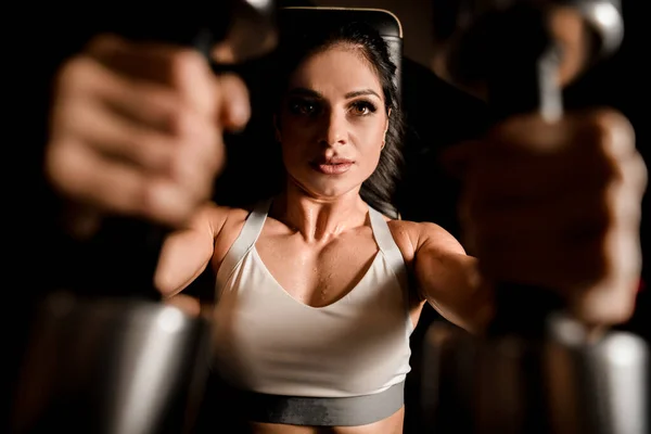 Närbild av kvinna som använder maskin för att pumpa grupp av muskler i gym. — Stockfoto
