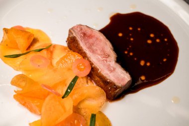 Tabağa yakından bak. Bir parça et, sos ve mandalina dilimleri..