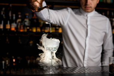 Şeffaf sıvı ve kalın beyaz dumanlı cam barın üzerinde duruyor.