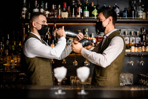 I baristi maschili stanno al bar e mescolano cocktail in agitatori d'acciaio — Foto Stock