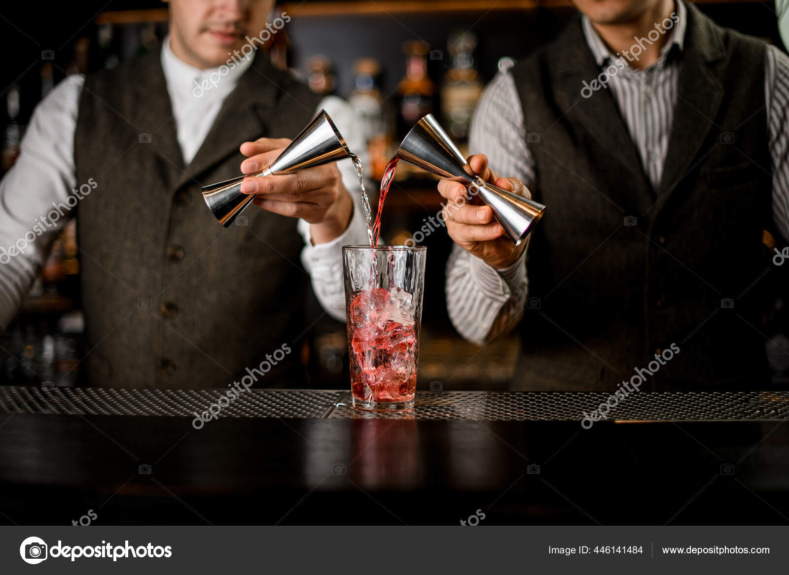 Bartender Holds In Hand Steel Jigger And Pours Drink From Bottle
