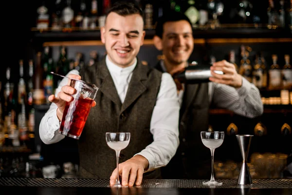 Sorridente garçom masculino derramando coquetel de copo para vidro no balcão de bar. — Fotografia de Stock