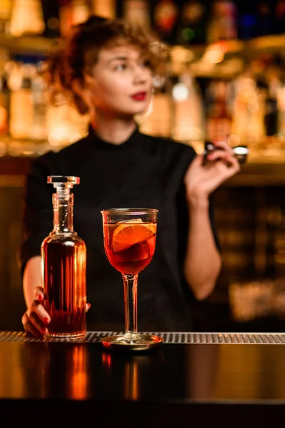 Uitzicht op glas van heldere cocktail op bar en fles in de hand van barman in de buurt — Stockfoto