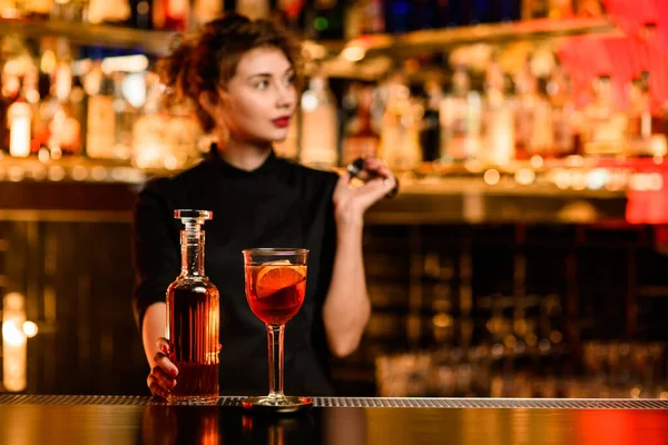 Uitzicht op glas met cocktail op bar en fles met drank in de hand van barman in de buurt — Stockfoto