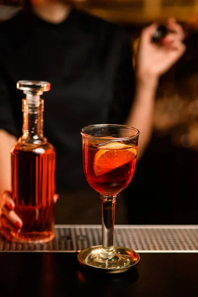 Close-up de vidro com coquetel no bar e garrafa com bebida na mão do barman nas proximidades — Fotografia de Stock