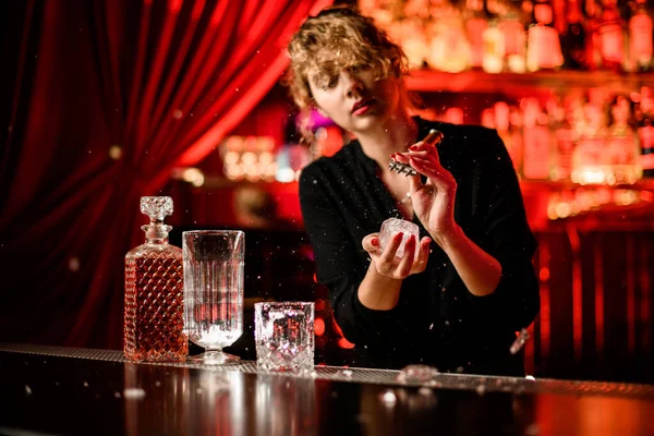 Mujer en el bar rompe gran pedazo de hielo con pico y pequeñas piezas vuelan alrededor — Foto de Stock