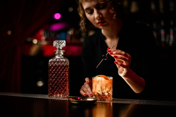 Vrouw barman netjes versiert glas koude alcoholische cocktail met olijf — Stockfoto