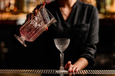 Barın tezgahına yakın plan cam ve bardakla kadının kokteylini karıştır.