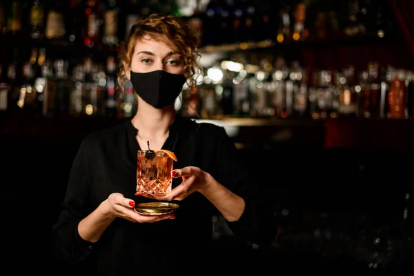 Vue de la femme en masque noir et tenant verre avec cocktail — Photo