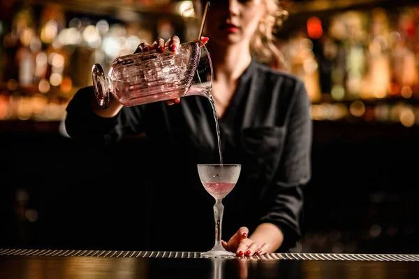Vista de cerca de la hermosa camarera hembra vertiendo cóctel de la taza de mezcla en cristal — Foto de Stock